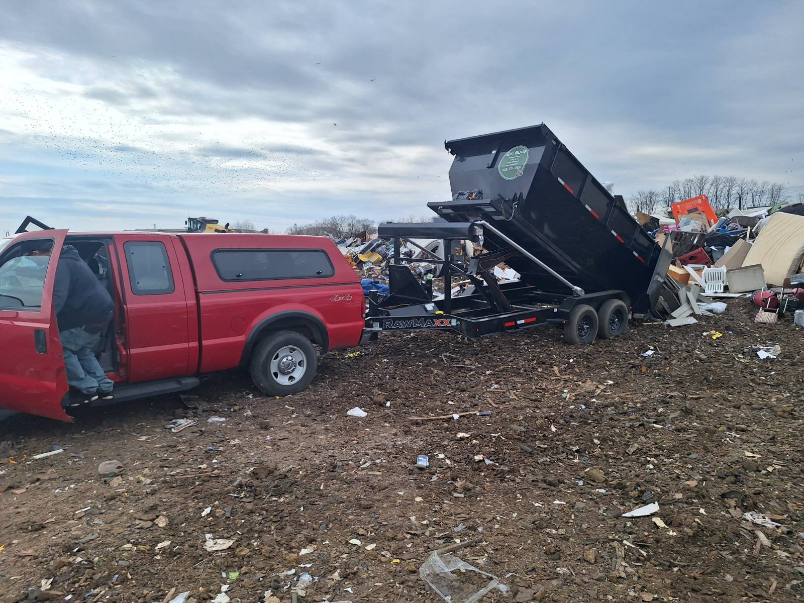 Red truck with dump trailer at cluttered waste disposal site
