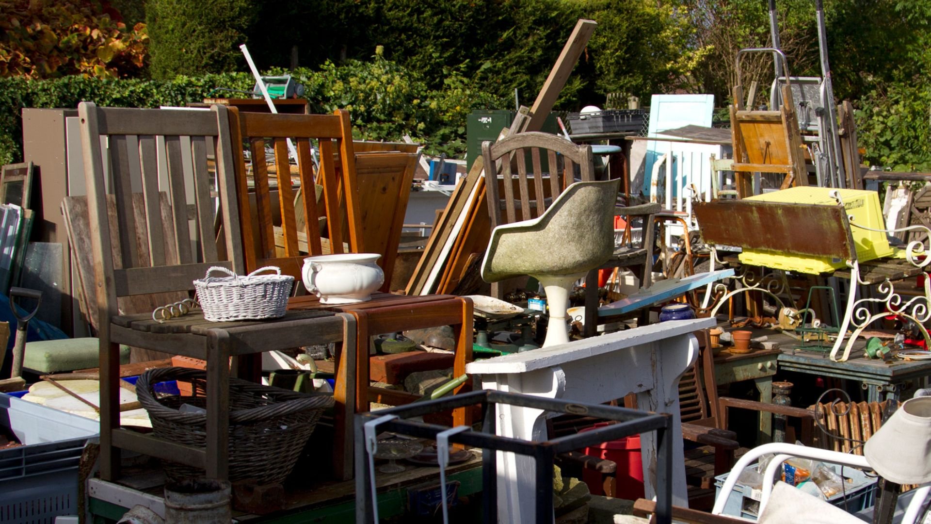 Cluttered outdoor yard with assorted vintage furniture, chairs, and random objects